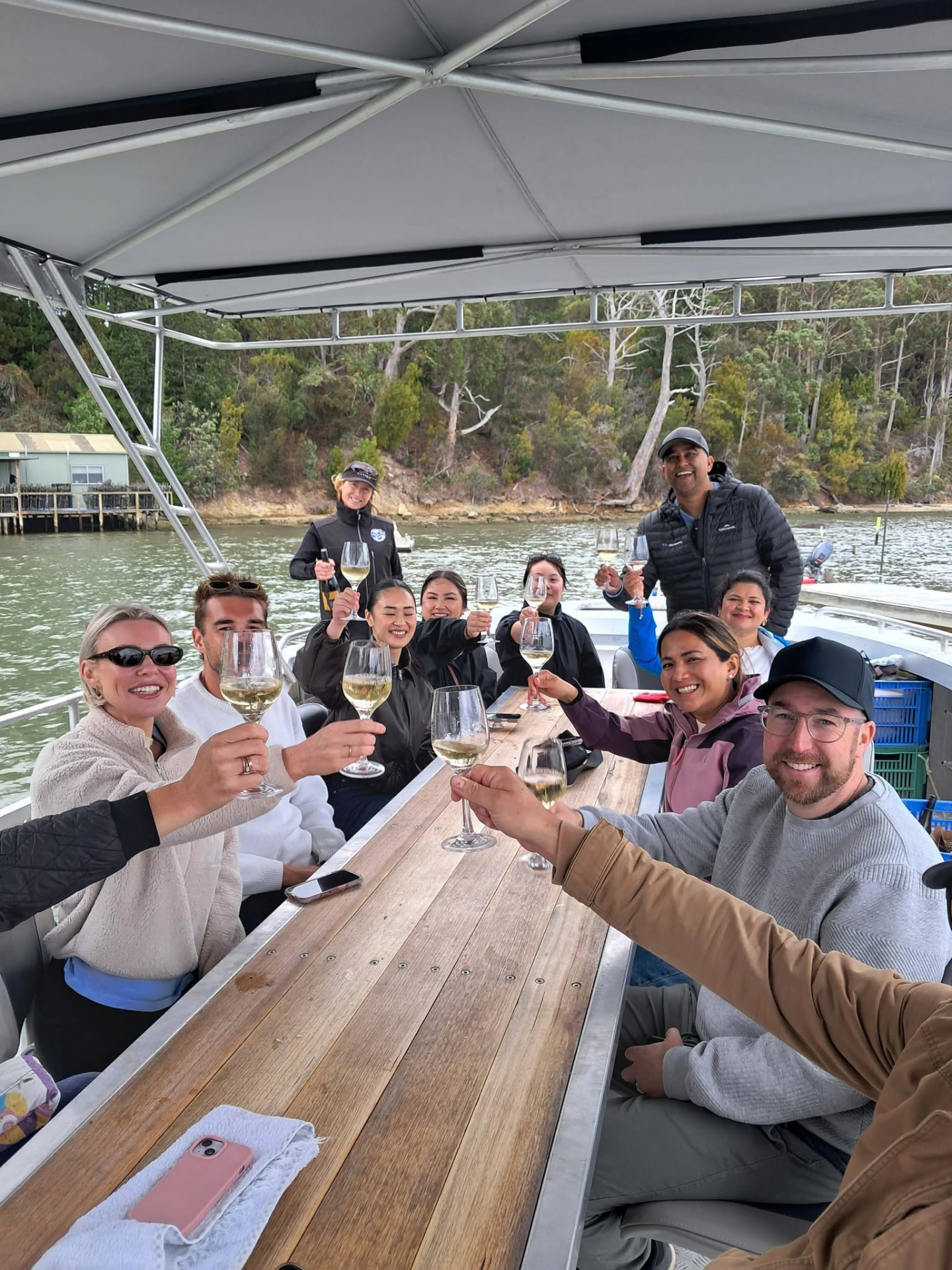 A full table of guests raising their wine glasses on the boat