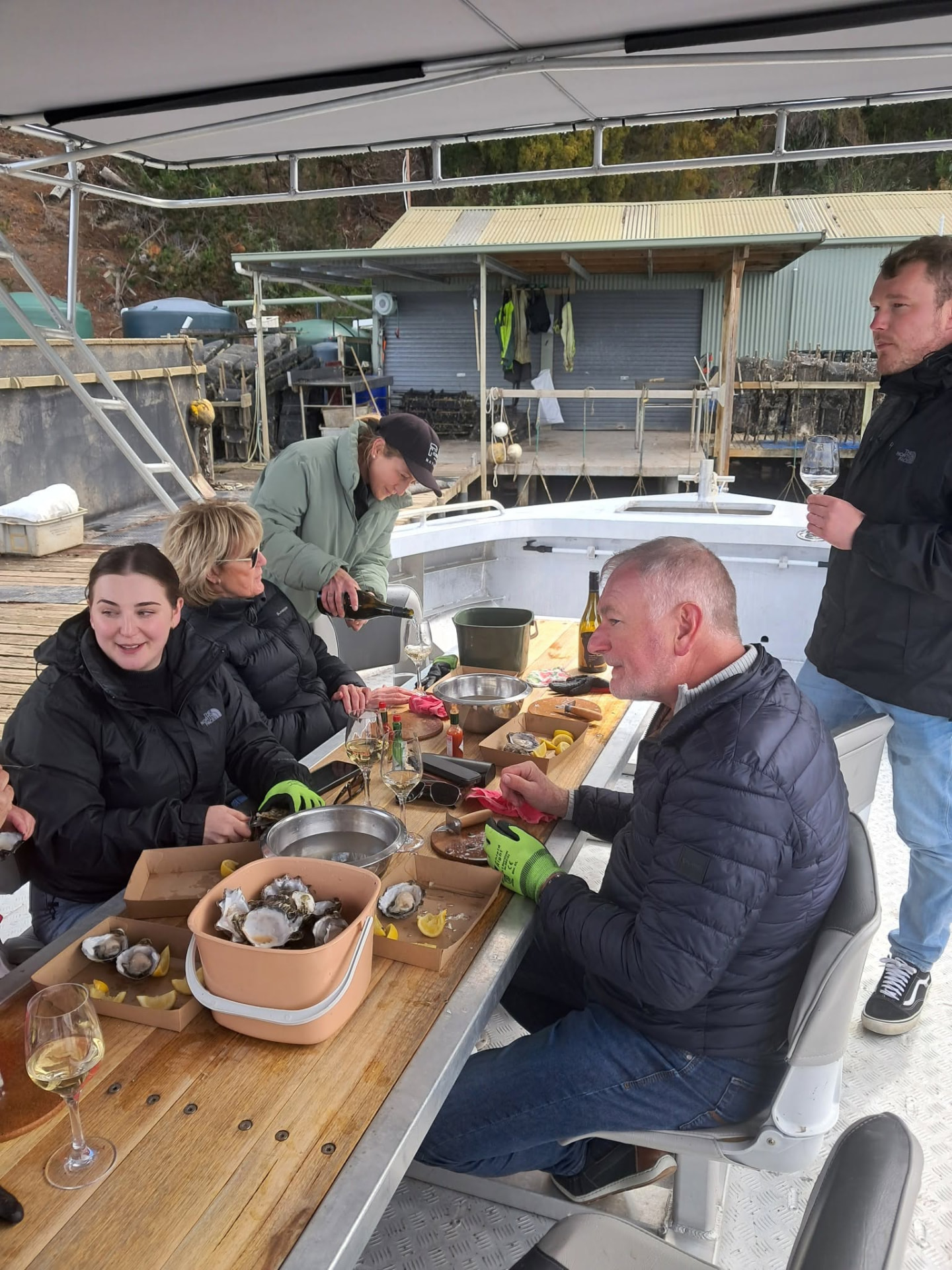 Wine being poured for guests eating oysters beside the oyster shed