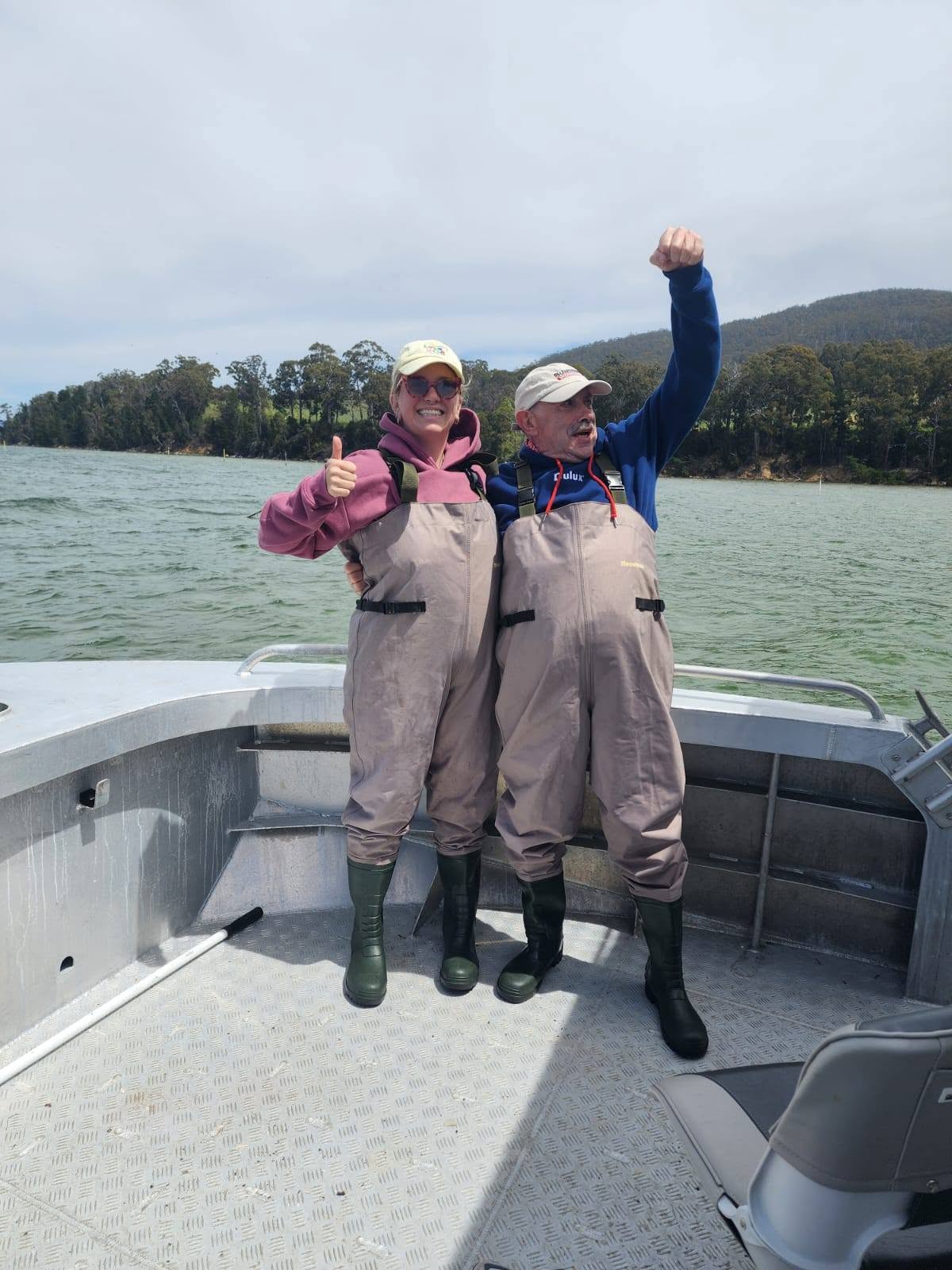 Two guests in waders celebrating on board on the D'Entrecasteaux Channel